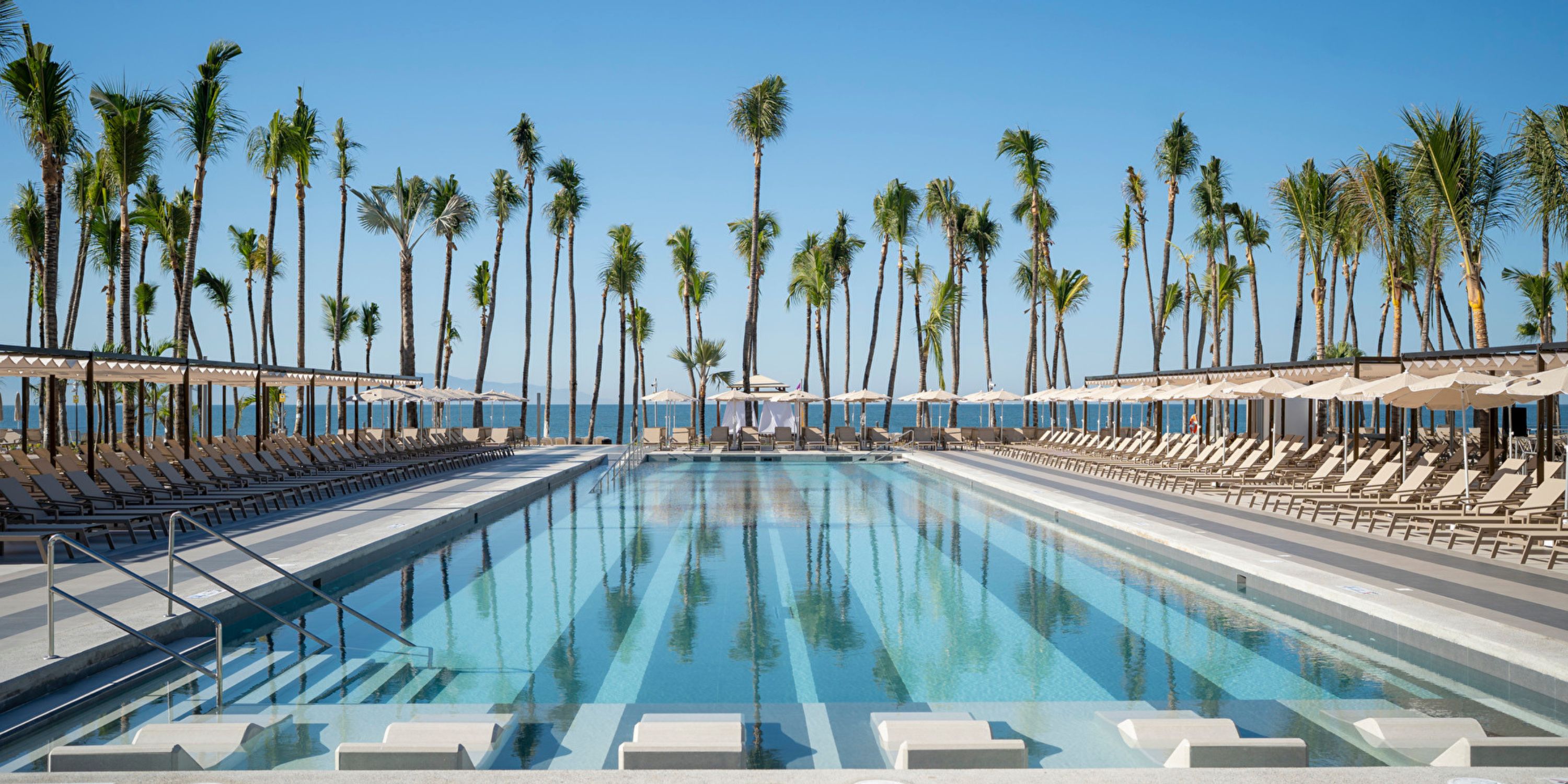 Hotel Riu Jalisco: Outdoor pool with lounge chairs and palm trees, ideal for a destination wedding.