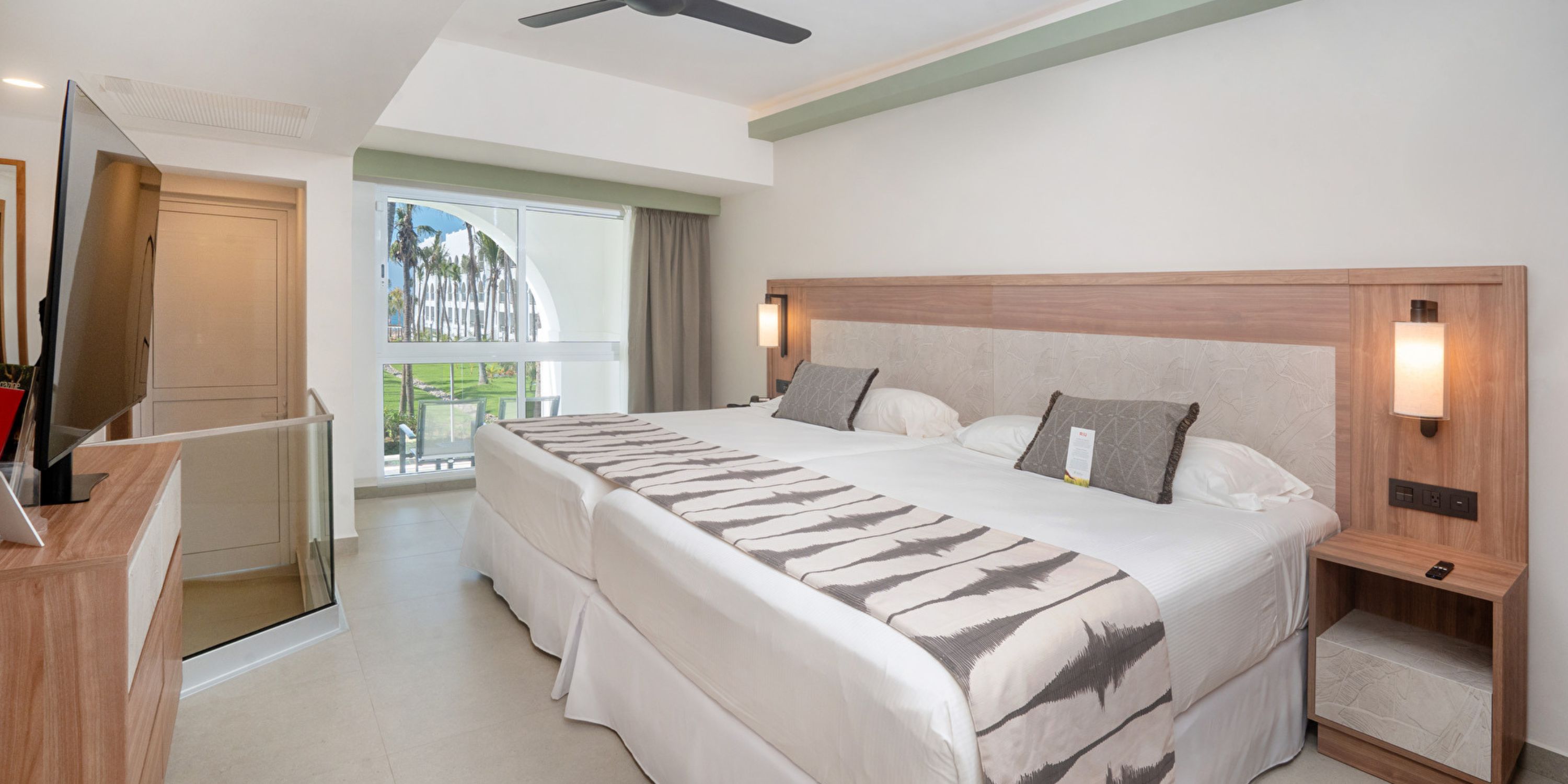 Hotel Riu Jalisco room with 2 large beds, TV, window, and modern decor—ideal for a destination wedding.