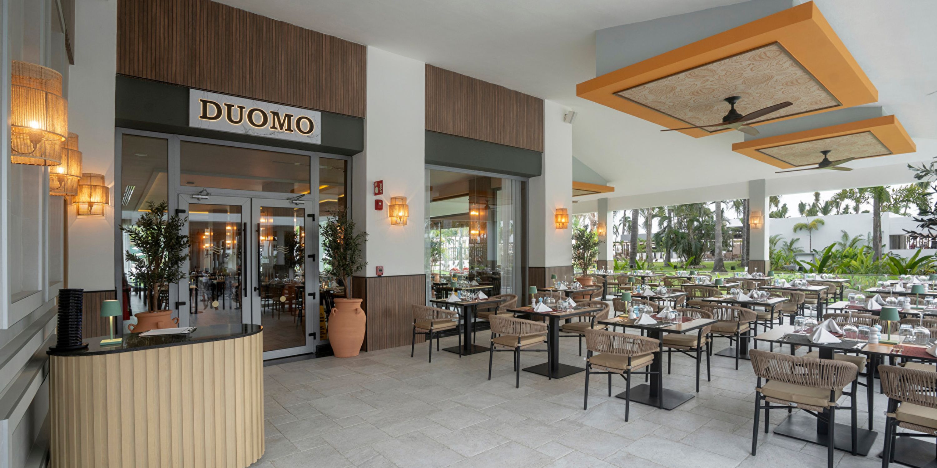 Outdoor dining area with set tables beside Hotel Riu Jalisco entrance, perfect for a destination wedding.