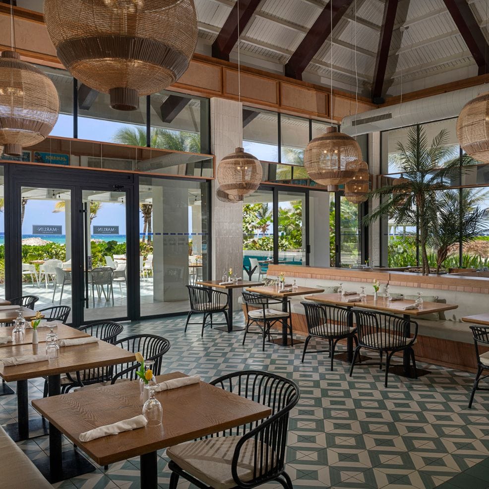 Chic restaurant with wooden tables, black chairs, and woven lights—perfect for a destination wedding.