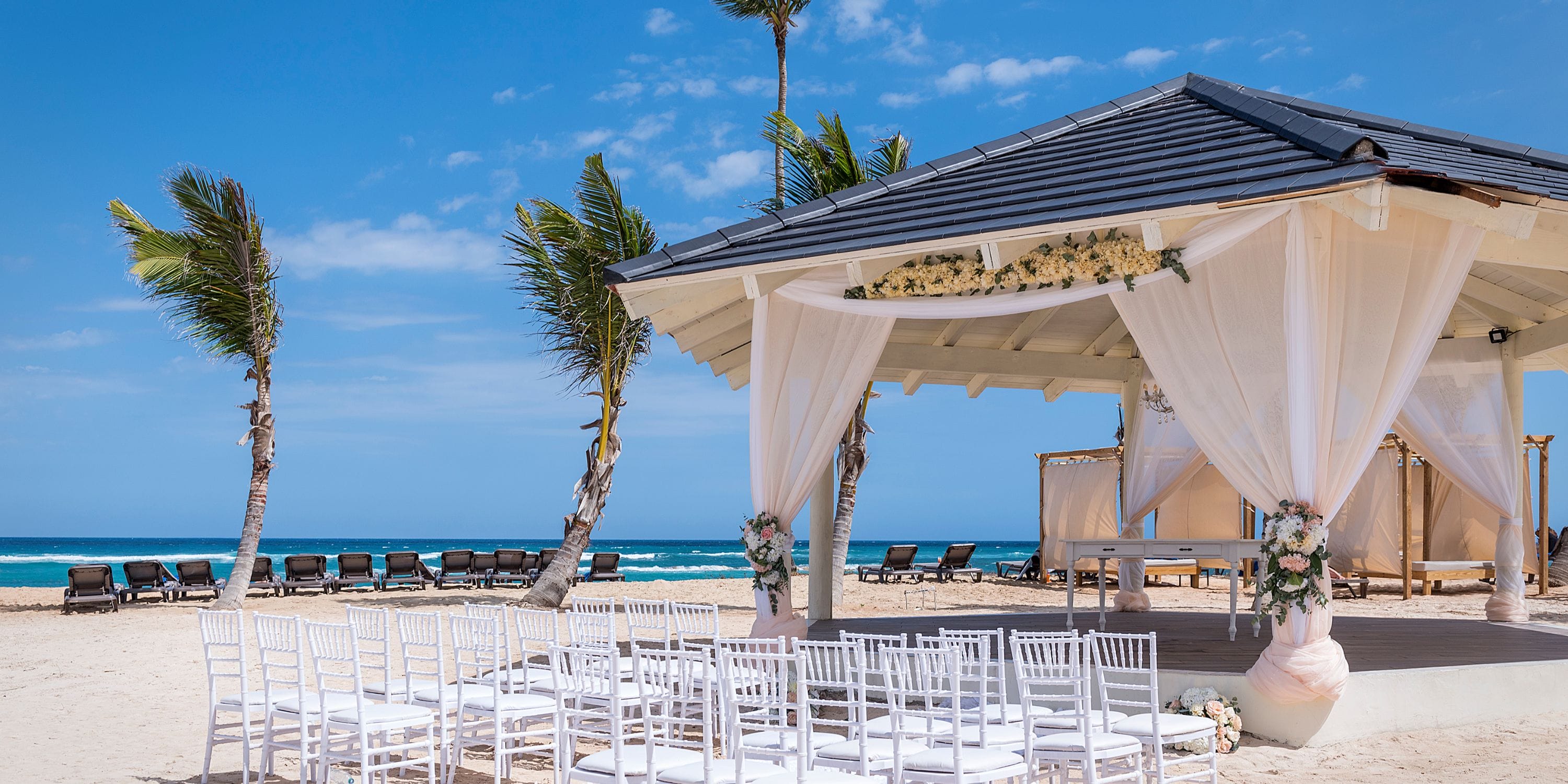 El Beso at Ocean El Faro features white chairs and a gazebo for a dreamy destination wedding by the sea.