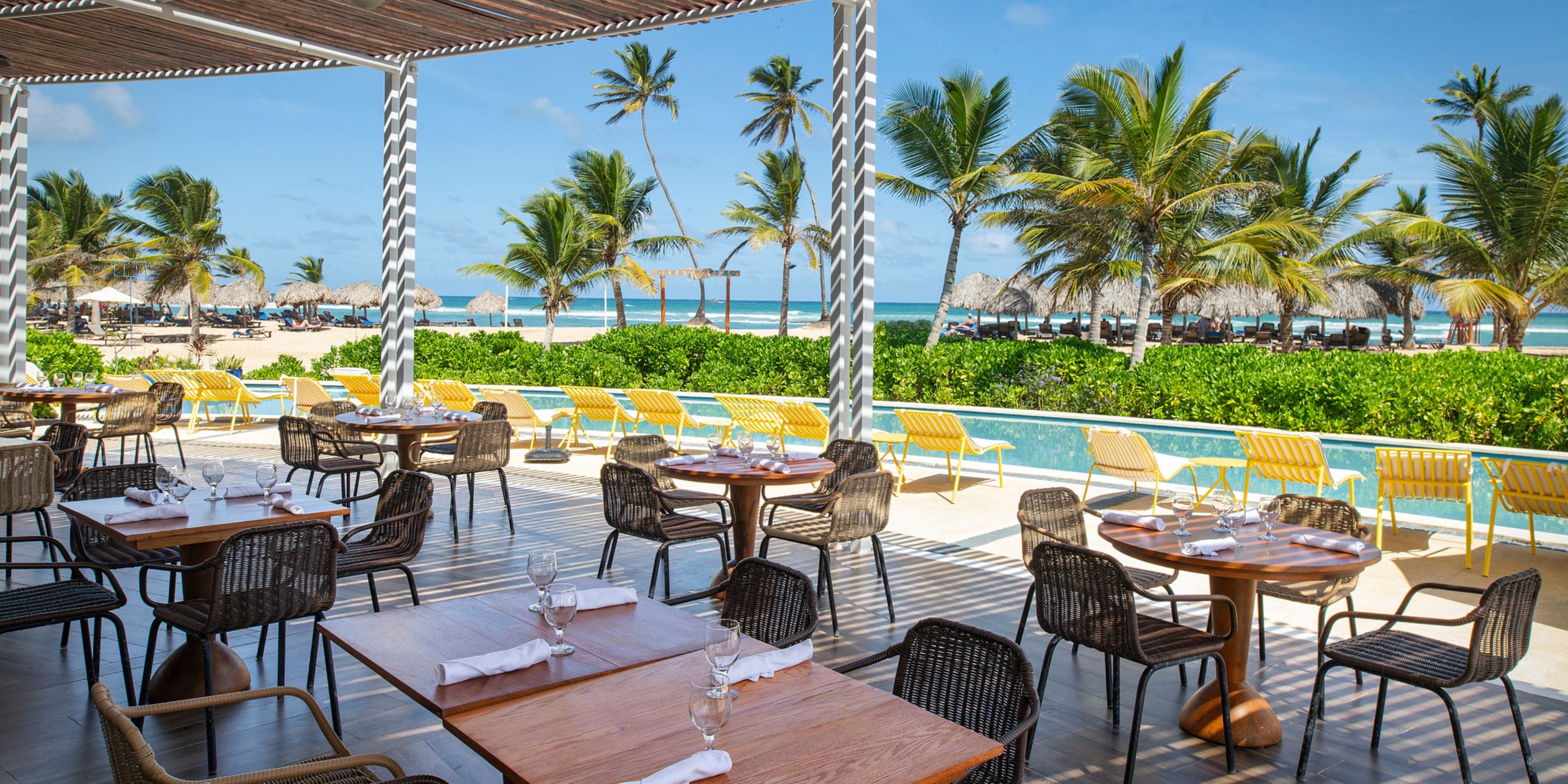 El Beso at Ocean El Faro: ideal for destination weddings with wood tables, pool views, palms, and beach.