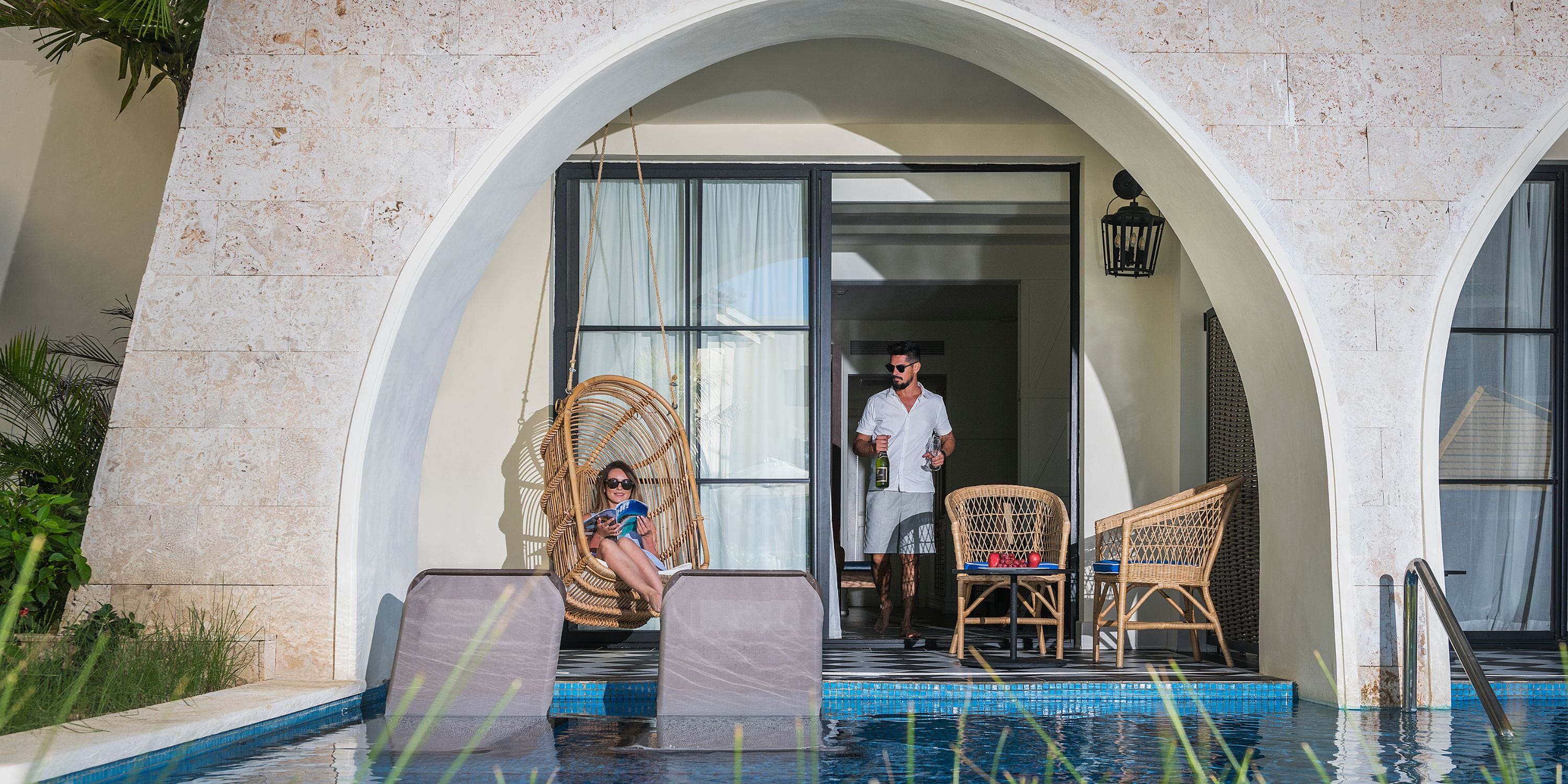 Two people sip drinks by the pool at El Beso, a popular spot for destination wedding celebrations.