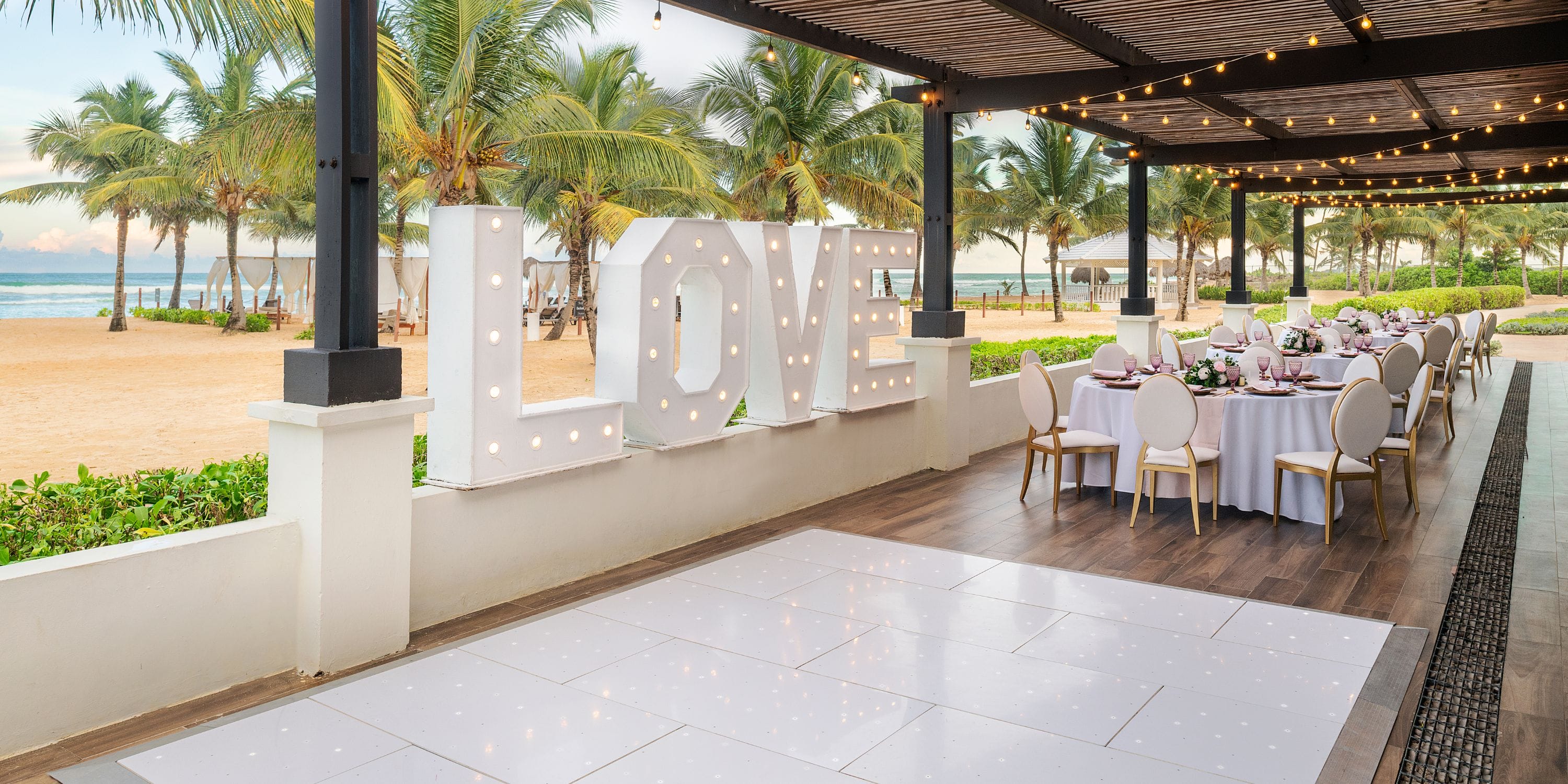El Beso at Ocean El Faro: destination wedding venue with "LOVE" sign and elegantly set round tables.