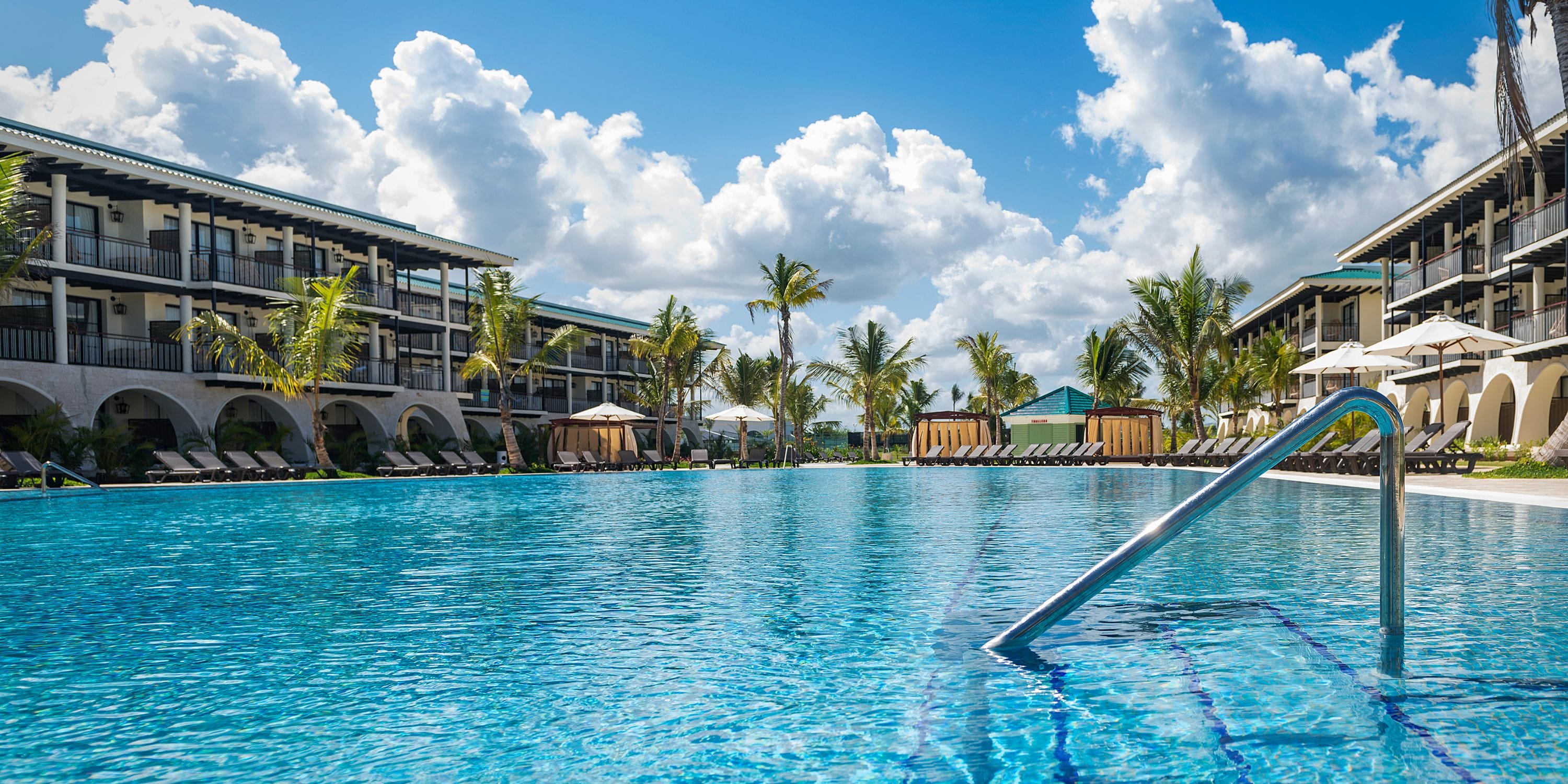 El Beso at Ocean El Faro: ideal destination wedding spot with outdoor pool, lounge chairs, and palm trees.