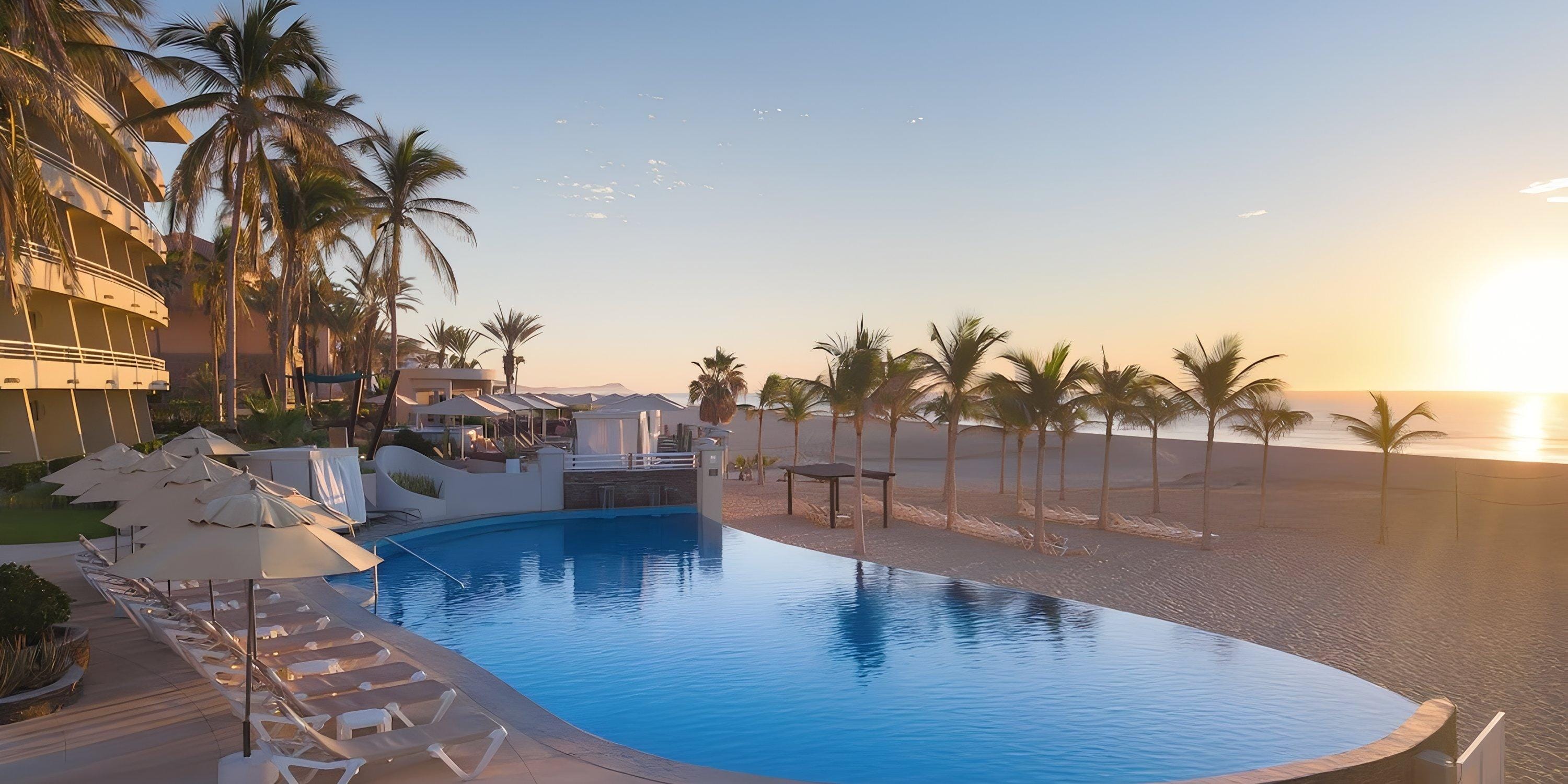 Barceló Grand Faro Los Cabos pool at sunrise, ideal for a destination wedding, with chairs and palm trees.