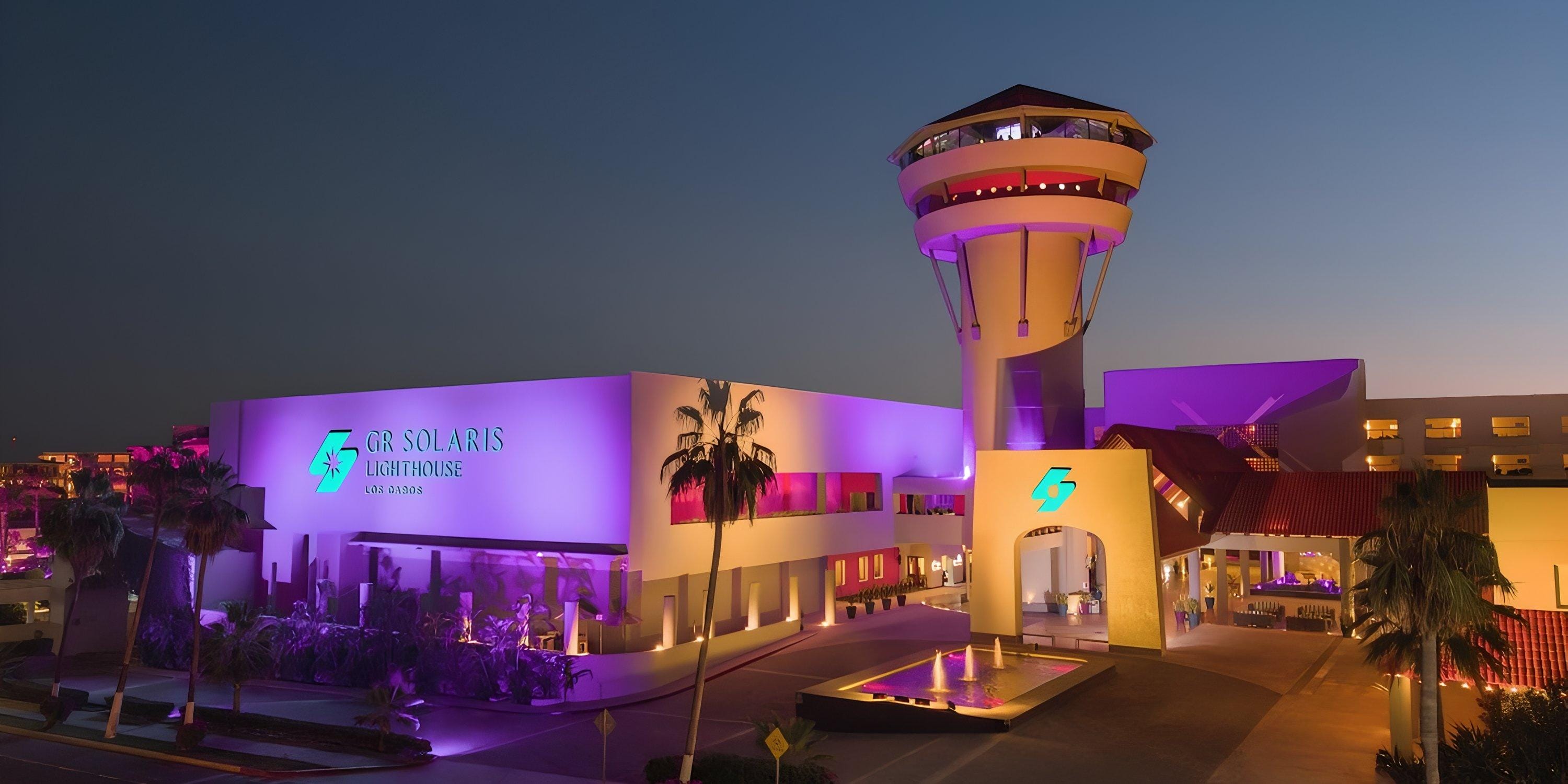 Barceló Grand Faro Los Cabos aglow in purple at dusk, perfect for a destination wedding backdrop.