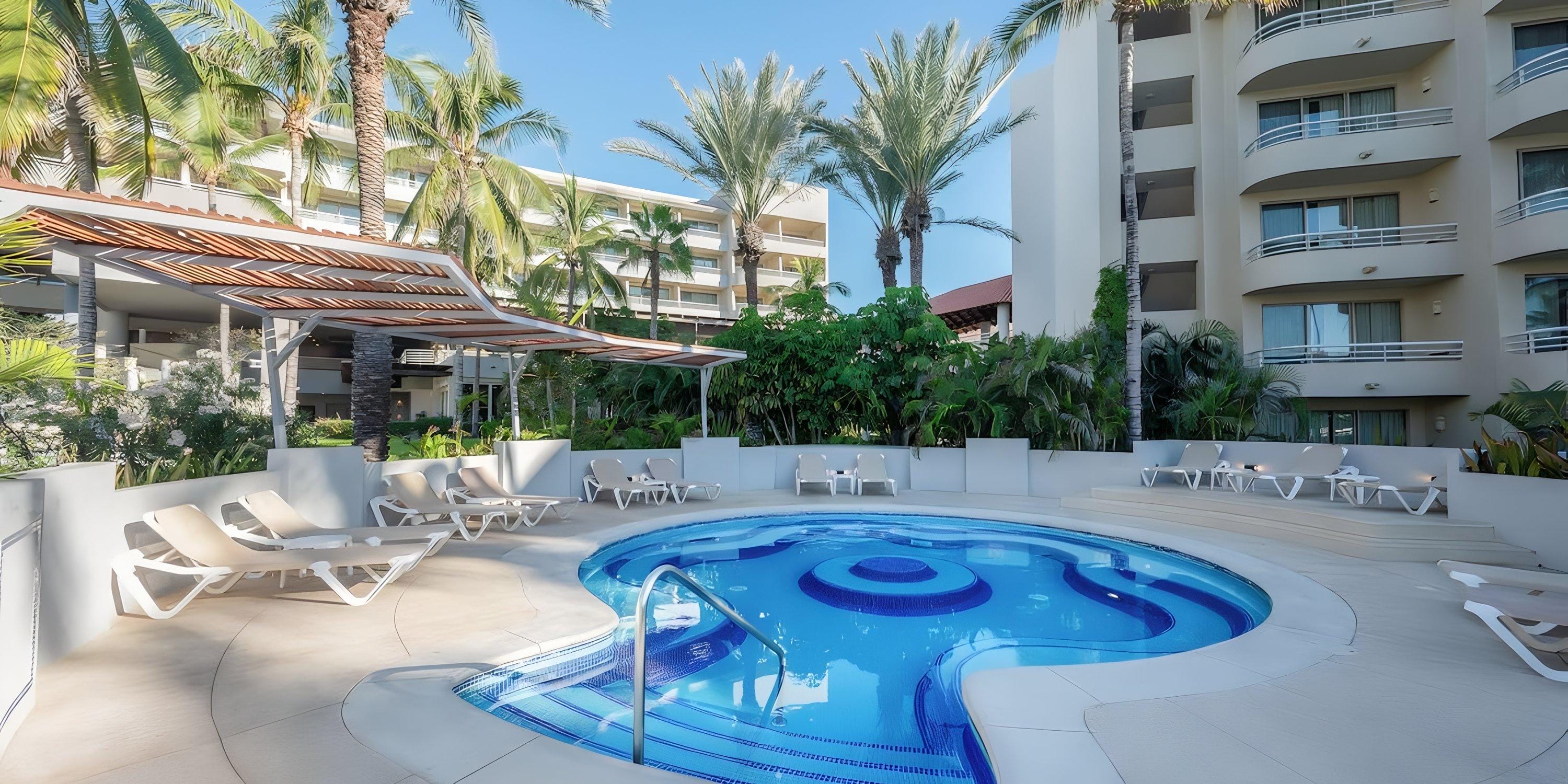 Barceló Grand Faro Los Cabos: Circular pool with built-in seating, lounge chairs, palm trees—ideal for a destination wedding.