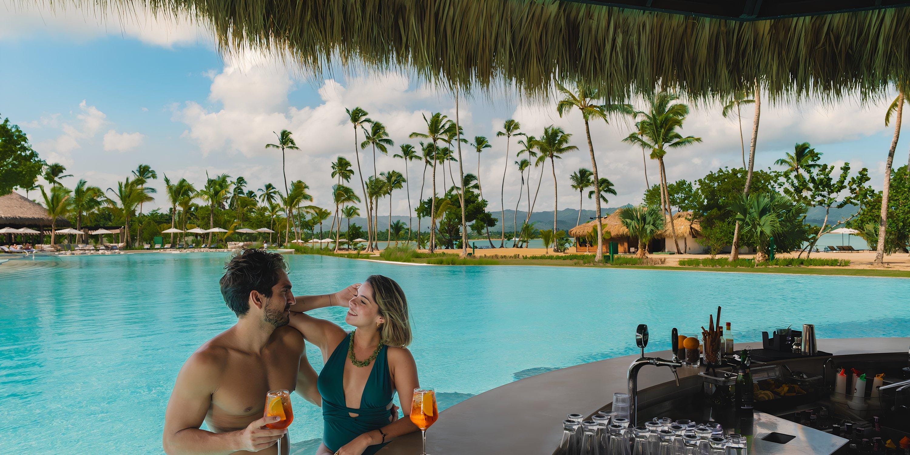 A couple enjoys drinks at the Hilton Cancun Mar Caribe swim-up pool bar, perfect for a destination wedding.