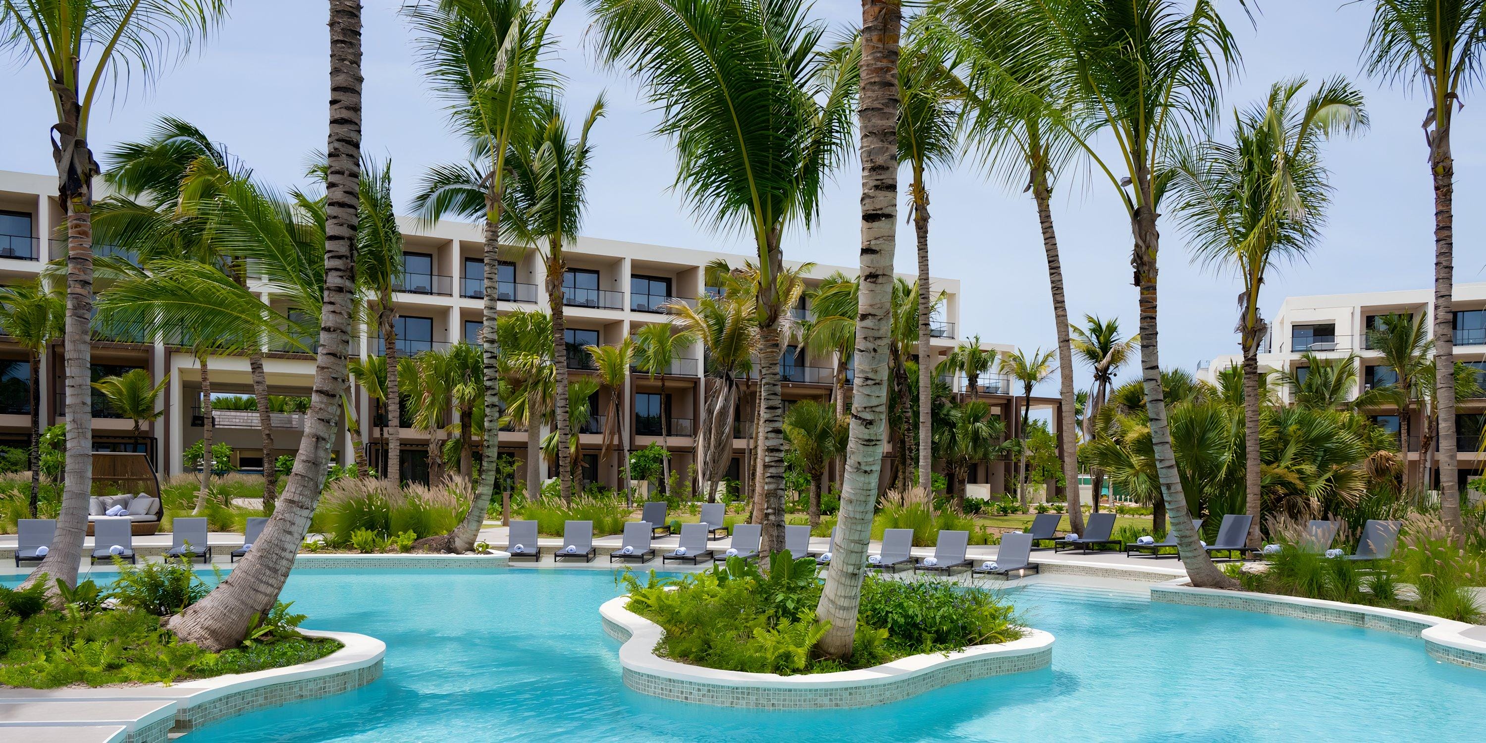 Outdoor pool with palm trees and lounge chairs, ideal for a destination wedding at Hilton Cancun Mar Caribe.
