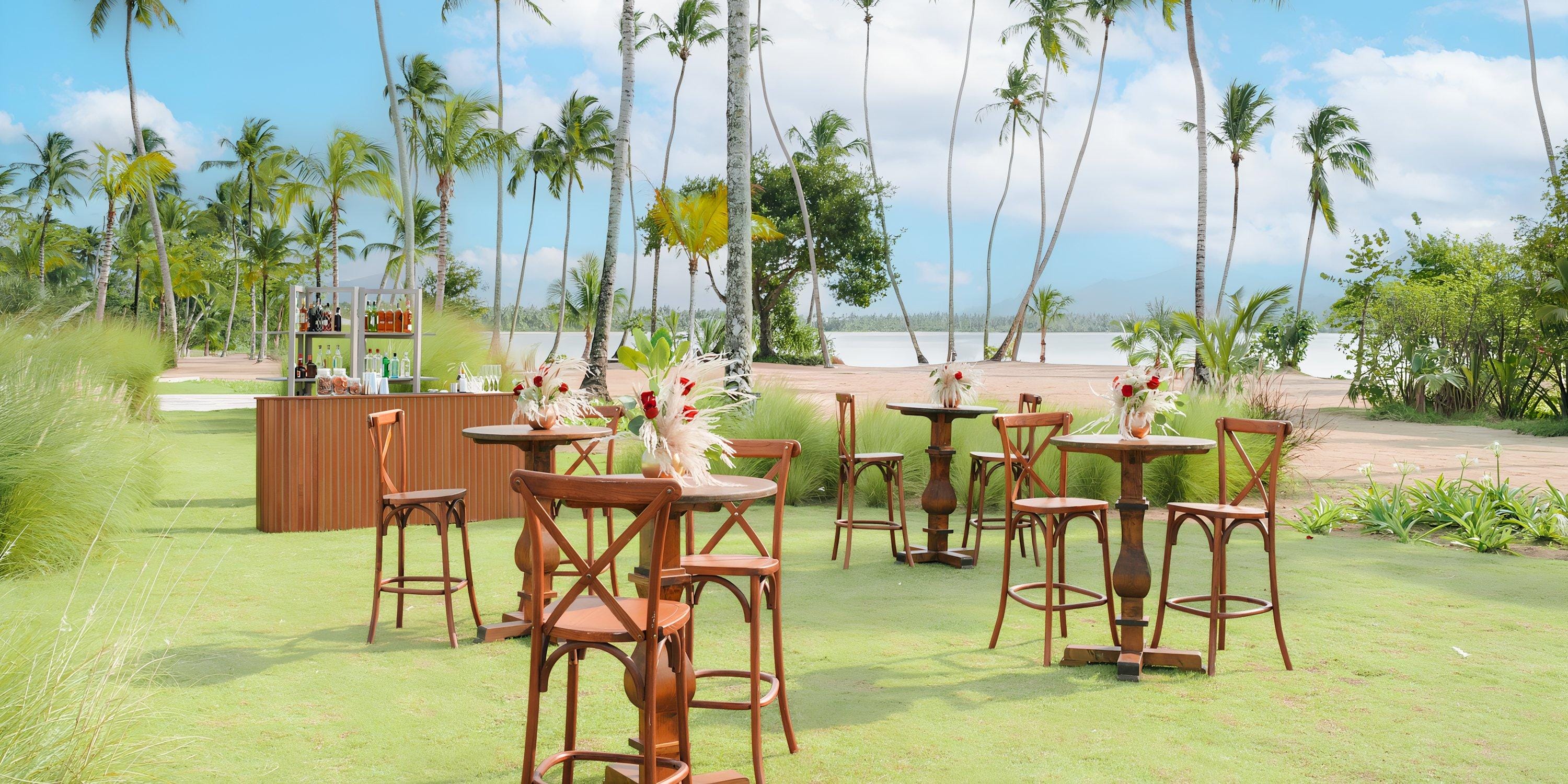 Hilton Cancun Mar Caribe: Outdoor cocktail tables and chairs on grass for a destination wedding, bar, palms, and beach view.