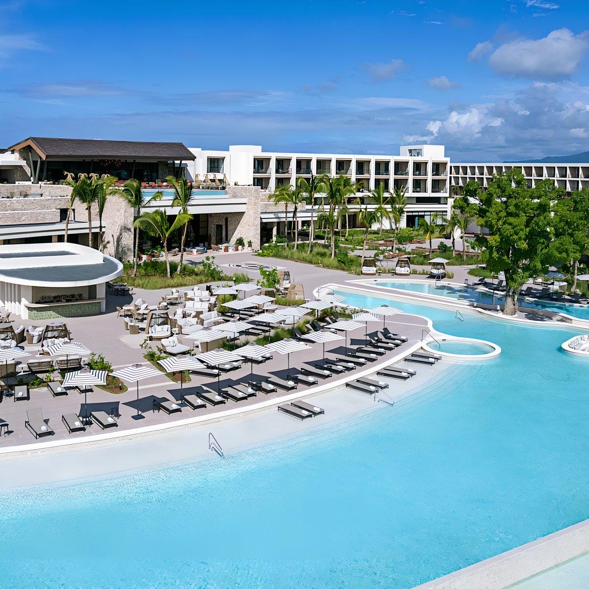 Hilton Cancun Mar Caribe: modern resort, ideal for destination weddings, with pool, palm trees, buildings.