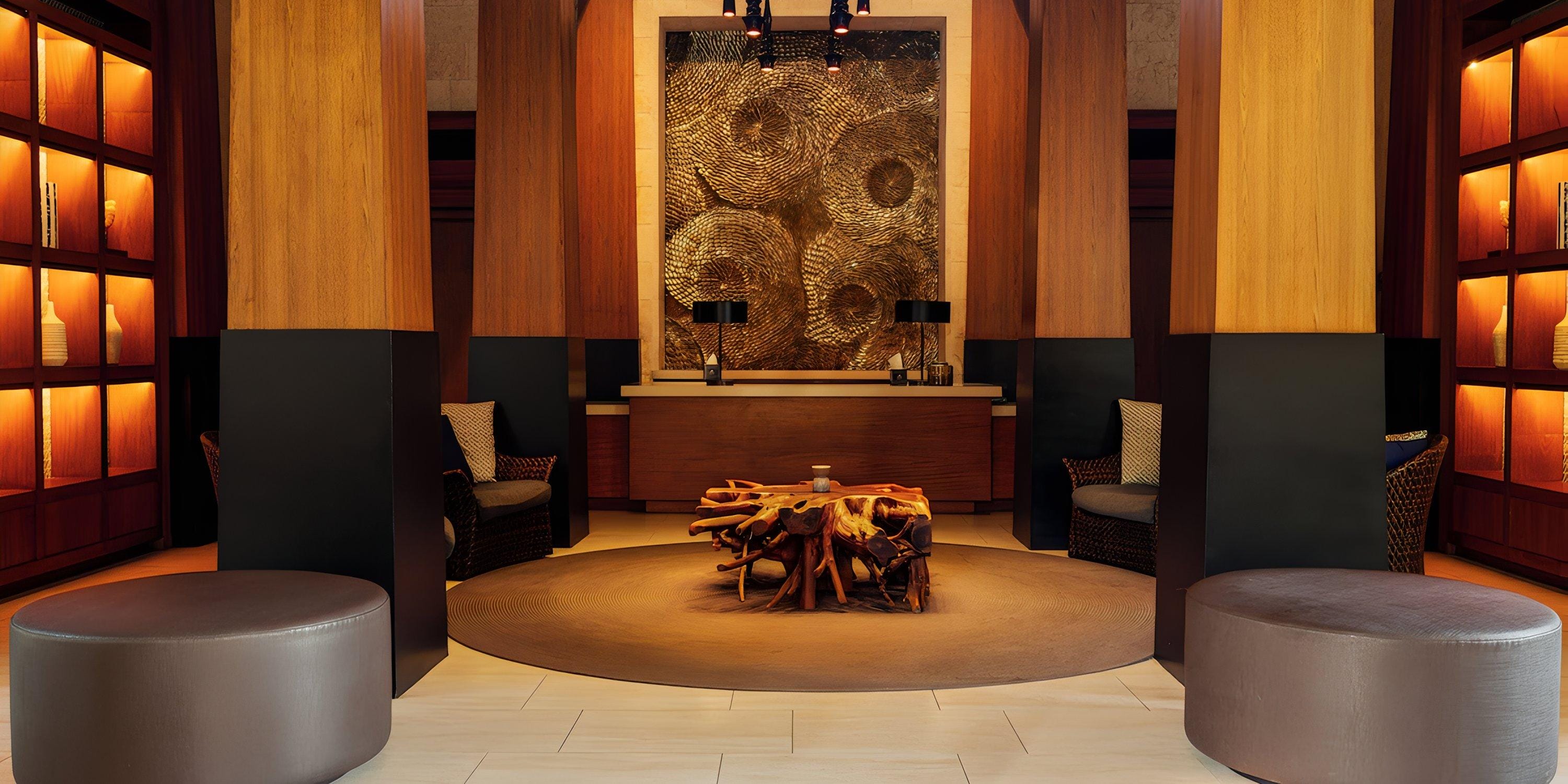 Lopesan Costa Bavaro lobby: wooden decor, round table, 2 chairs, lit shelves—perfect for a destination wedding.