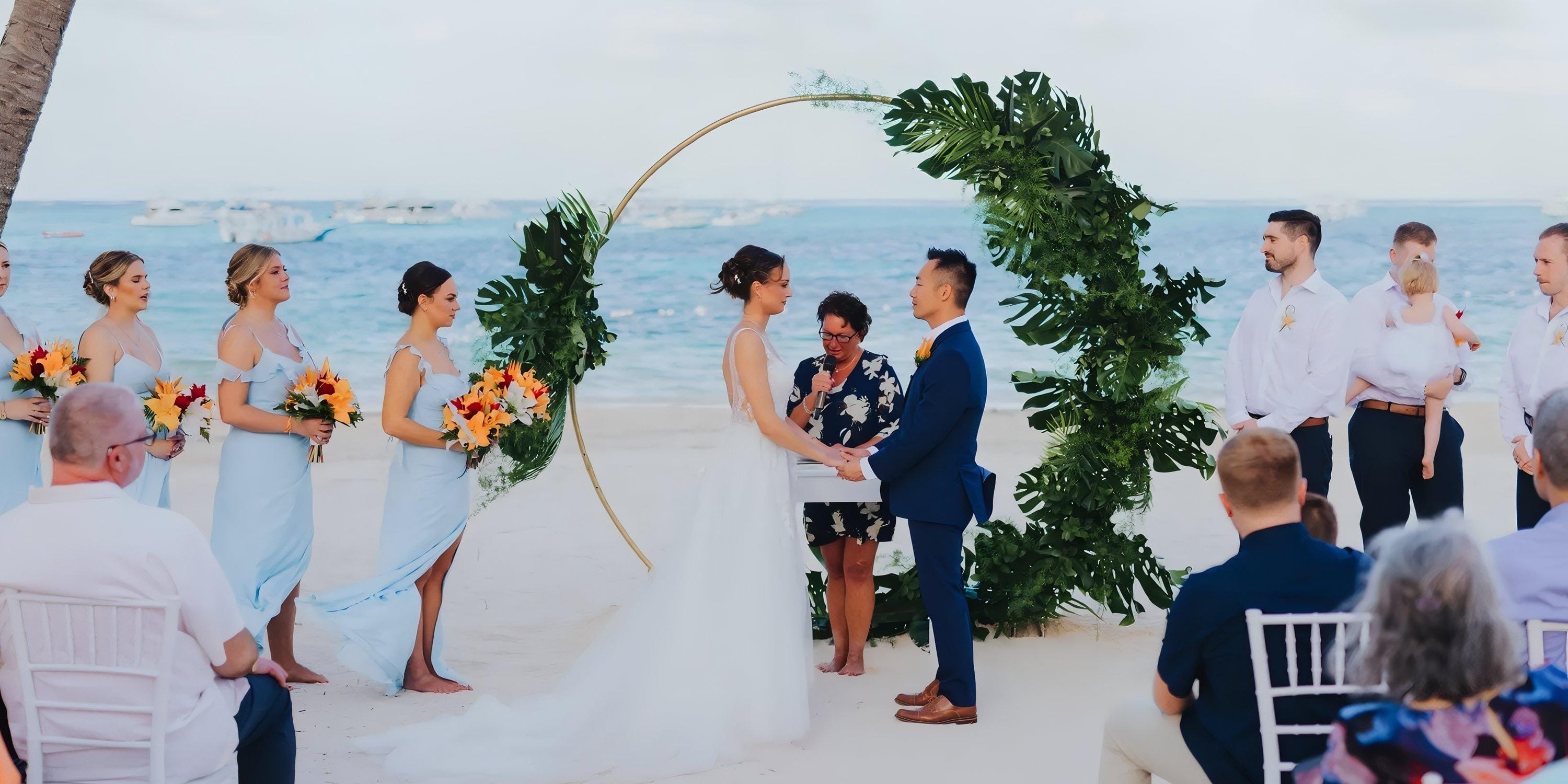 A couple's destination wedding at Lopesan Costa Bavaro, holding hands at a beach altar before guests.