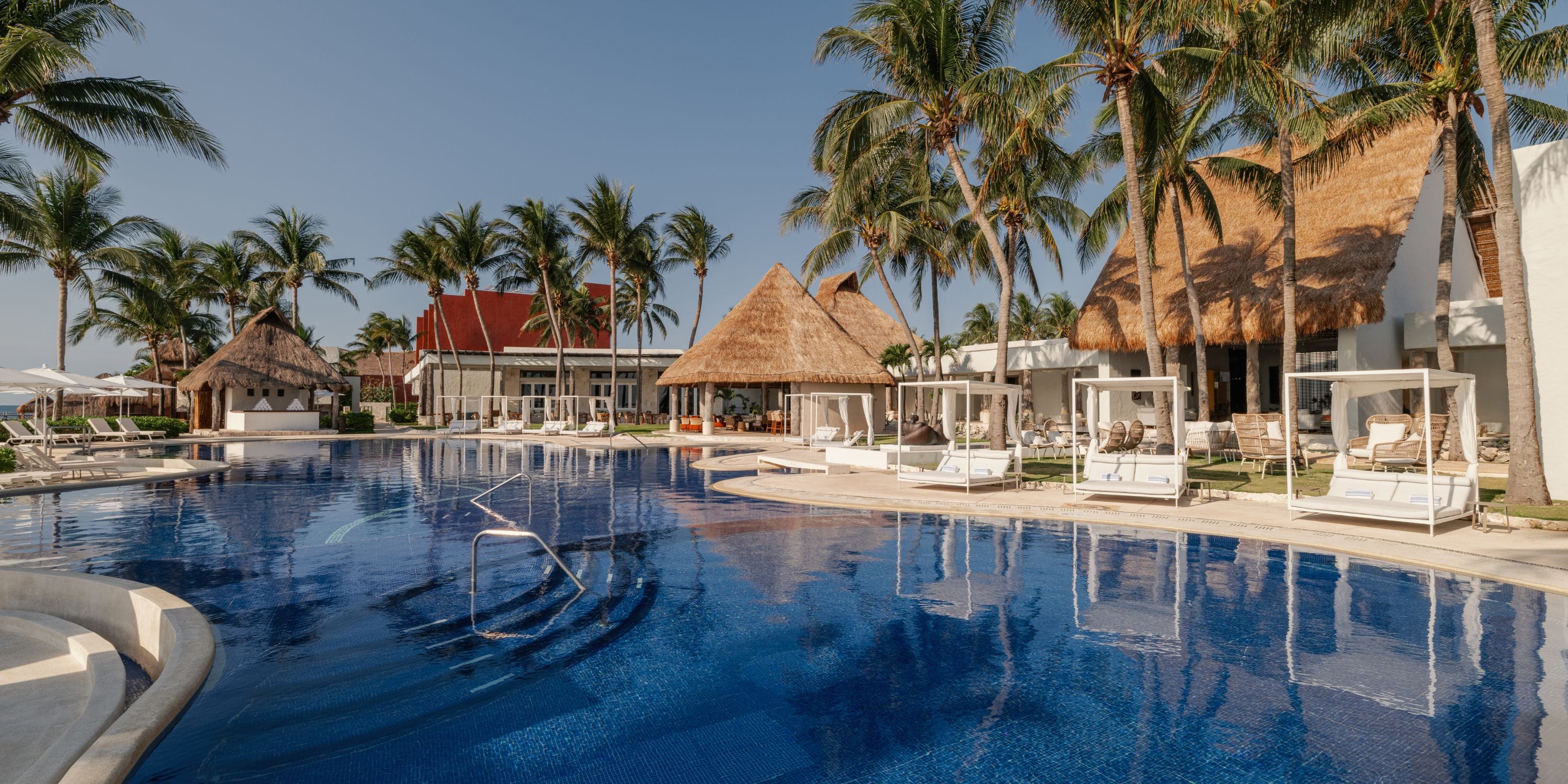 Royalton Riviera Cancun's pool—a dream destination wedding spot with palm trees and thatched roofs.