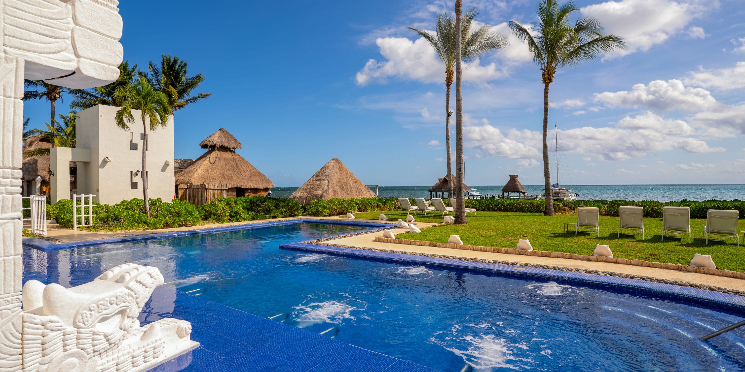 Blue-tiled pool, bubbling jets, palm trees, and ocean—an ideal Royalton destination wedding spot.