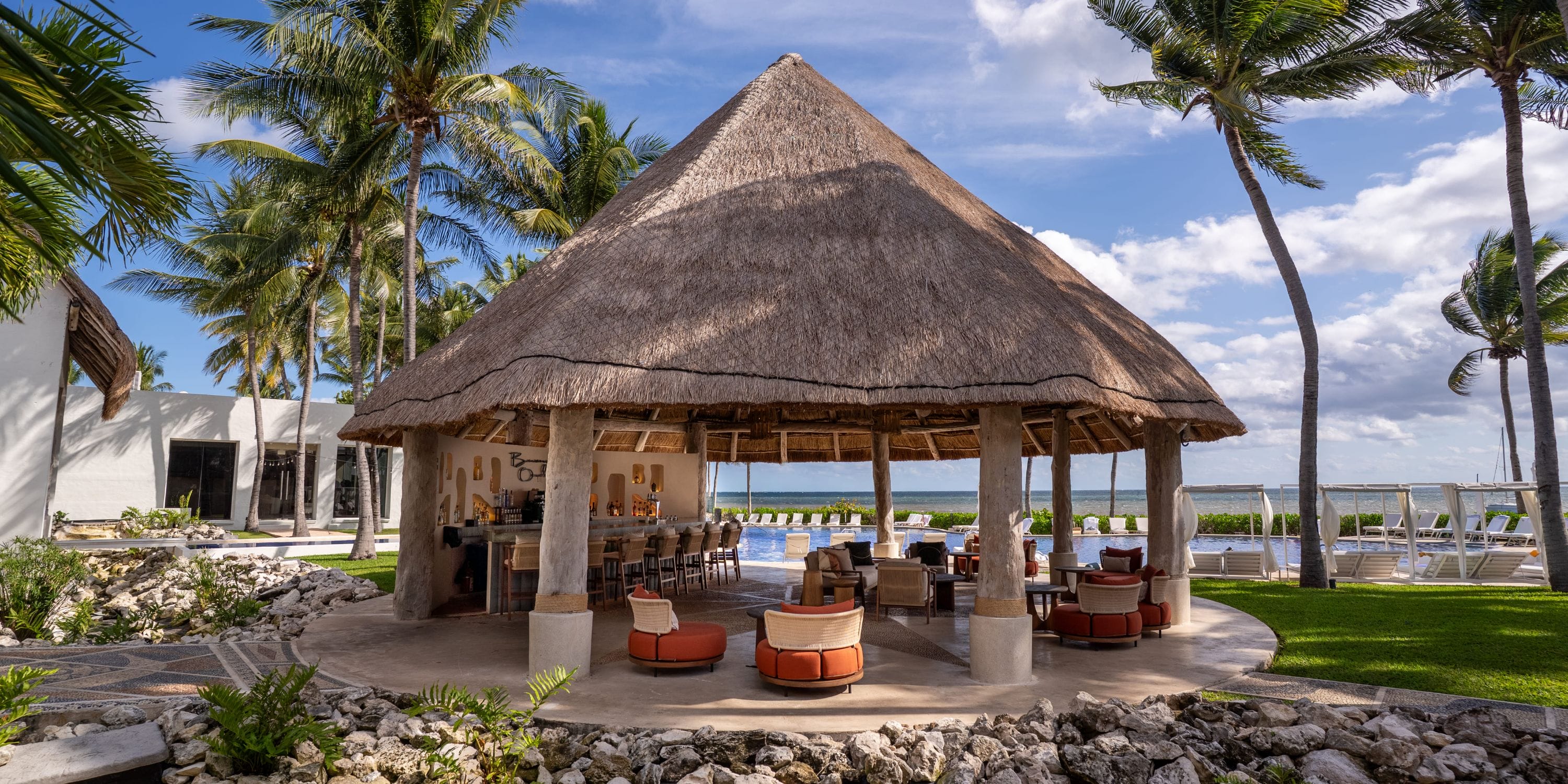 Thatched-roof bar, seating, palm trees, ocean views—ideal for a Royalton Riviera Cancun wedding.