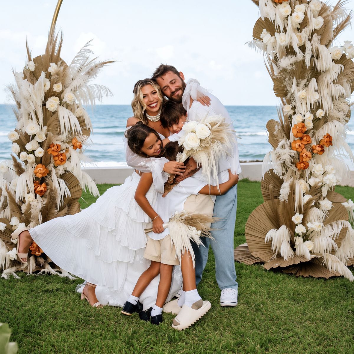 Kayleigh and Isaac: Family in white embraces at destination wedding on floral-filled oceanfront.